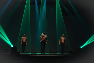 Drie dansers op podium in groene spotlights