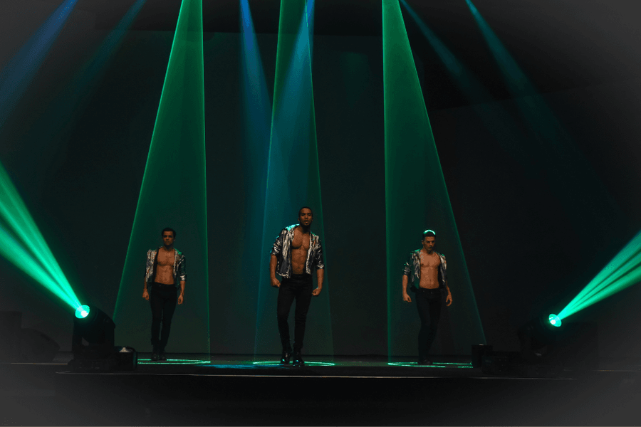 Drie dansers op podium in groene spotlights