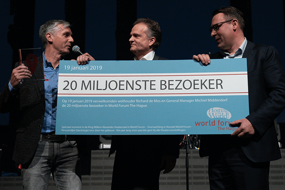 Herre Roelevink uit Pijnacker wordt als 20 miljoenste bezoeker van World Forum The Hague getrakteerd door Wethouder Richard de Mos en General Manager Michiel Middendorf